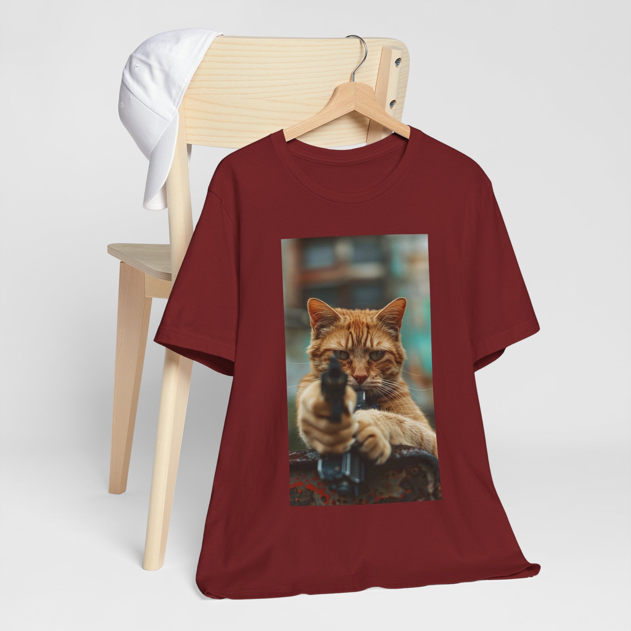 The image displays a sleek women's jersey short sleeve t-shirt, featuring a detailed and humorous image of a cat in role of hitman. The t-shirt is modeled to showcase its flattering fit and soft fabric, highlighting how fashion can meet fun and functionality