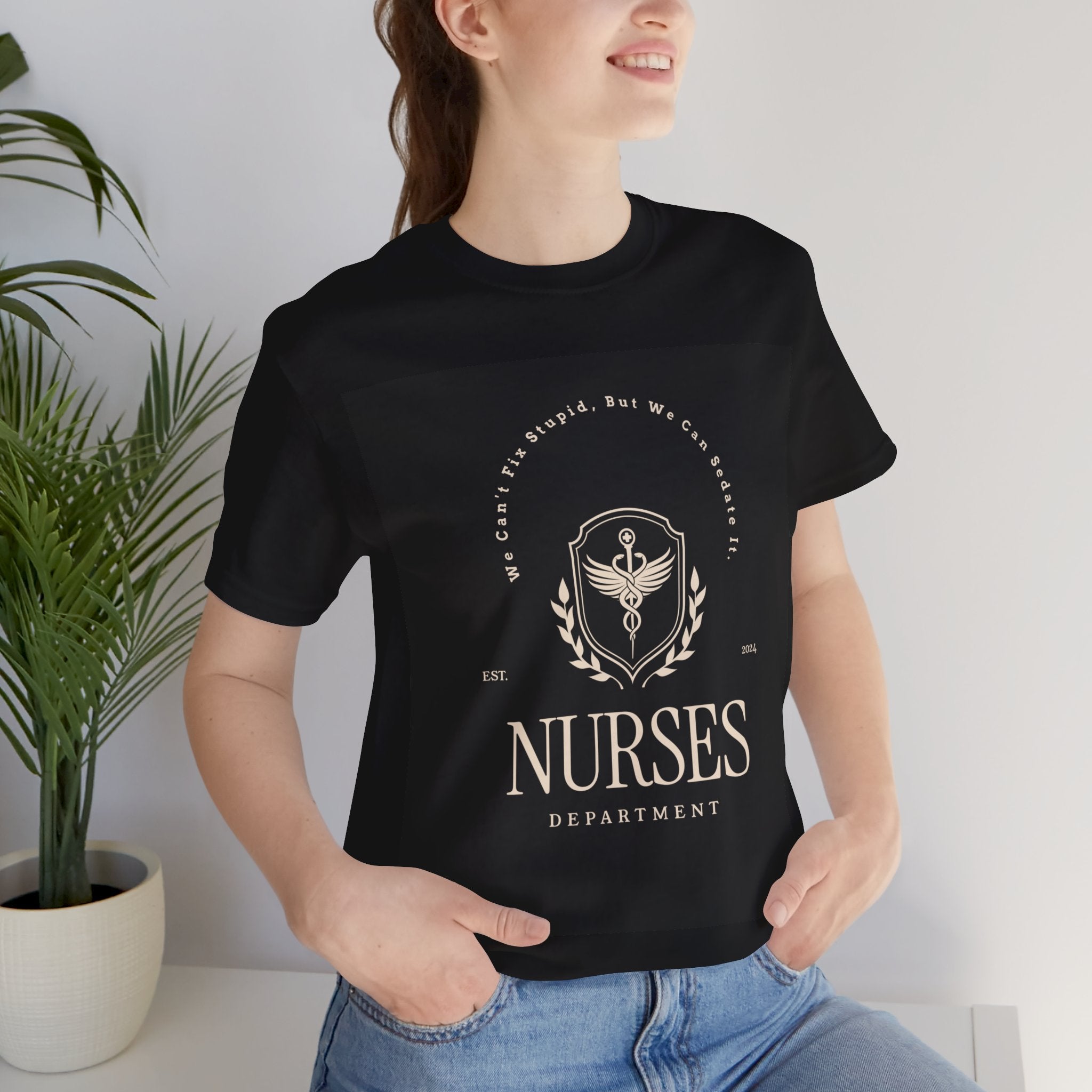 The image features a high-quality, soft, unisex jersey tee in a classic cut. The front proudly displays the humorous "We Can't Fix Stupid, But We Can Sedate It" slogan, with a customizable "Est. Date" below that adds a personal touch to the shirt. It's the perfect combination of comfort and sass that any nurse would be proud to wear on their day off or under their scrubs.